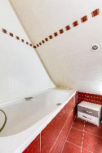 red-tiled bathroom with bathtub in a 2-bedroom Paris apartment