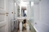 white bathroom with a bathtub and a sink in a 1-bedroom Paris luxury apartment