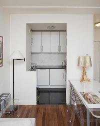 a dining area with a white table and clear dining chairs for 4, and well-equipped kitchen in a 1-bed