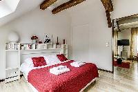 second bedroom with a queen-size bed and shelves in a 2-bedroom Paris luxury apartment