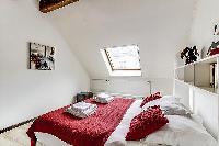 second bedroom with a queen-size bed and shelves in a 2-bedroom Paris luxury apartment