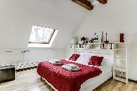 second bedroom with a queen-size bed and shelves in a 2-bedroom Paris luxury apartment