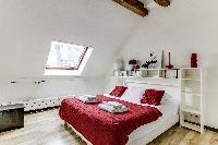 second bedroom with a queen-size bed and shelves in a 2-bedroom Paris luxury apartment