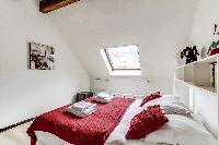 second bedroom with a queen-size bed and shelves in a 2-bedroom Paris luxury apartment