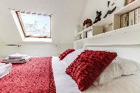 second bedroom with a queen-size bed and shelves in a 2-bedroom Paris luxury apartment