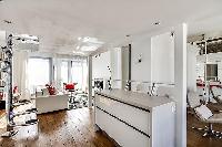 white kitchen bar counter with two tall chairs in a 1-bedroom loft Paris luxury apartment
