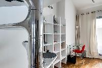 unique and modern spiral staircase, shelves, and study desk and chair in a 1-bedroom loft Paris luxu