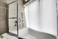 contemporary bathroom with toilet, sink, towel rack, and a bathtub with a detachable shower head in 