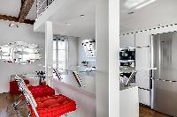 white kitchen bar counter with two tall chairs in a 1-bedroom loft Paris luxury apartment