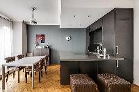 chic dining area with a table and six chairs with fully-equipped kitchen in a 2-bedroom paris luxury