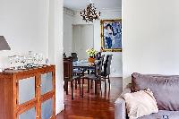 elegant dining area with a long table, six chairs, and paintings in a 3-bedroom Paris luxury apartme