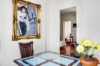 elegant dining area with a long table, six chairs, and paintings in a 3-bedroom Paris luxury apartme