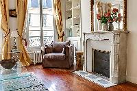 living area with an armchair, a fireplace, and shelves in a 3-bedroom Paris luxury apartment