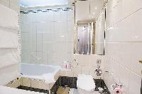 elegant bathroom with a full bathtub, a detachable shower head, built-in cabinets, a sink, and a van