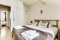 master bedroom with queen-size bed, fresh linens and towels in a 3-bedroom Paris luxury apartment