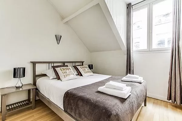 master bedroom with queen-size bed, fresh linens and towels in a 3-bedroom Paris luxury apartment
