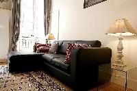 comfortable living room with L-shaped sofa, two armchairs, a center table, and a media shelf with te