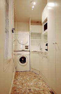 A washing machine, iron, ironing board, and clothes dryer in a 1-bedroom Paris luxury