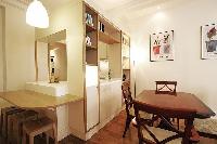 dining area with a four-seater dining set, a television, breakfast bar, and stools in a 1-bedroom Pa