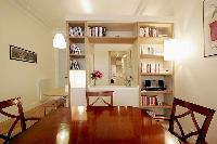 dining area with a four-seater dining set, bookshelves, breakfast bar, and stools in a 1-bedroom Par