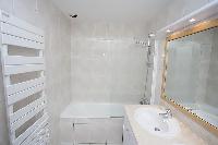white bathroom with built-in cabinet, double sinks, toilet, and bathtub in a 2-bedroom Paris luxury 