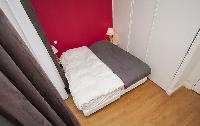 second bedroom with two single beds, two bedside tables with lamps, and a French window with courtya