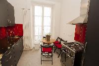 modern well-equipped kitchen with small dining table and 4 seats in a 2-bedroom Paris luxury apartme