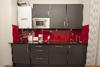 modern well-equipped kitchen in ed and gray hues in a 2-bedroom Paris luxury apartmentmodern well-eq
