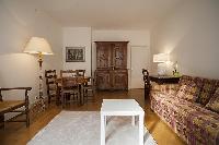 living area with a sofa, a center table, a desk, a chair, and a lamp in a 2-bedroom Paris luxury apa