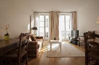 living area with a sofa, a center table, a desk, a chair, a TV and a lamp in a 2-bedroom Paris luxur