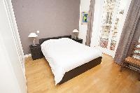 master bedroom with a queen-size bed, two bedside tables with lamps, a chair, a cabinet, and a Frenc