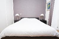 master bedroom with a queen-size bed, two bedside tables with lamps in a 2-bedroom Paris luxury apar