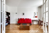 a study room with a second sofa, a study desk and table, chairs, and cabinets in a 2-bedroom Paris l