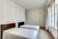 second bedroom with two single beds and a built-in closet in a 2-bedroom Paris luxury apartment