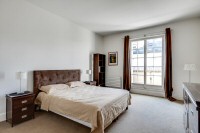 master bedroom is furnished with a queen-size bed, a large cabinet, a shelf, a nightstand, and two b