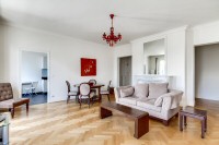 living area furnished with a sofa, an armchair, and a media shelf with television in a 2-bedroom Par