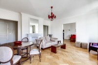 living area furnished with a sofa, an armchair, and a media shelf with television in a 2-bedroom Par