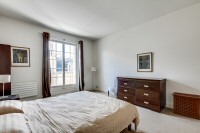 master bedroom is furnished with a queen-size bed, a large cabinet, a shelf, a nightstand, and two b