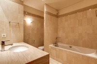first bathroom elegantly furnished with a sink, a mirror, a toilet, and a full bathroom with a detac