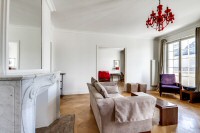 living area furnished with a sofa, an armchair, and a media shelf with television in a 2-bedroom Par
