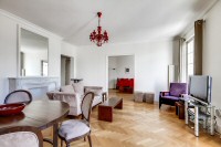 living area furnished with a sofa, an armchair, and a media shelf with television in a 2-bedroom Par
