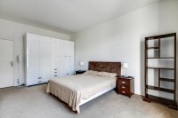 master bedroom is furnished with a queen-size bed, a large cabinet, a shelf, a nightstand, and two b