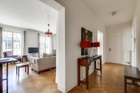 hall and living area furnished with a sofa, an armchair, and a media shelf with television in a 2-be