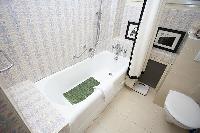 elegant bathroom with bathtub, toilet, and detachable shower head in a 1-bedroom Paris luxury apartm