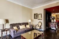 comfortable sofa bed, lamps, armchairs, and gold center table in a 1-bedroom Paris luxury apartment