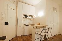 space efficient kitchen with breakfast bar and stools in a 1-bedroom Paris luxury apartment