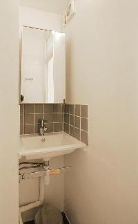 bathroom with a sink, a mirror, a toilet, and a shower area in a 1-bedroom Paris luxury apartment