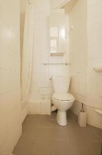 bathroom with a sink, a mirror, a toilet, and a shower area in a 1-bedroom Paris luxury apartment