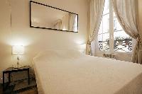 sleeping area with two bedside tables, two lamps, and a double bed in a 1-bedroom Paris luxury apart