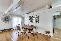 dining area with a long wooden table and six modern chairs in Paris luxury apartment